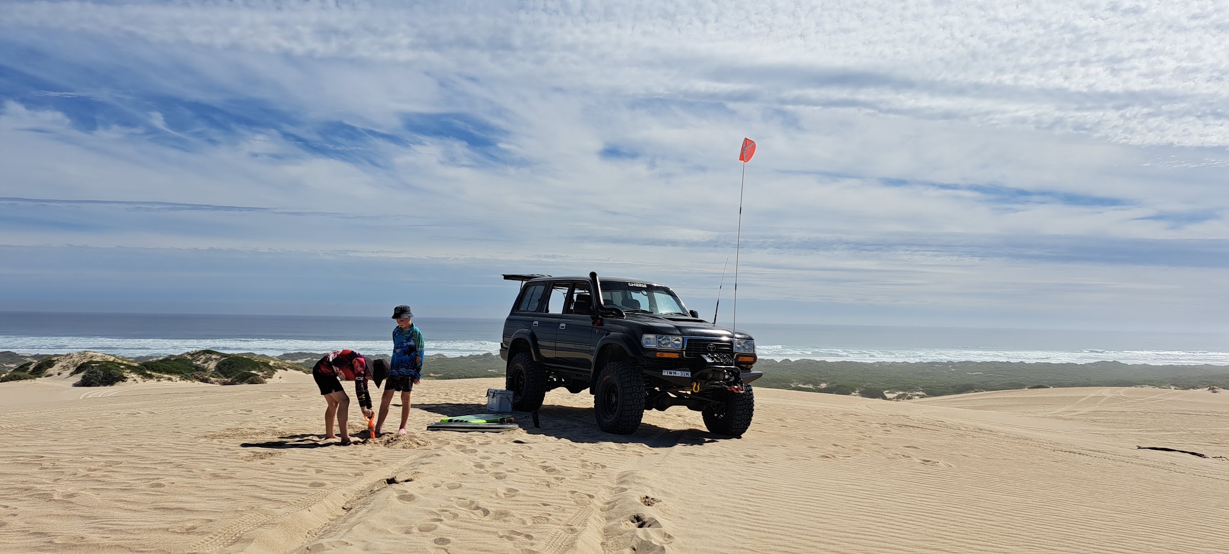 A lifted Land Cruiser parked on the sand dunes above the surf on the coast near Portland