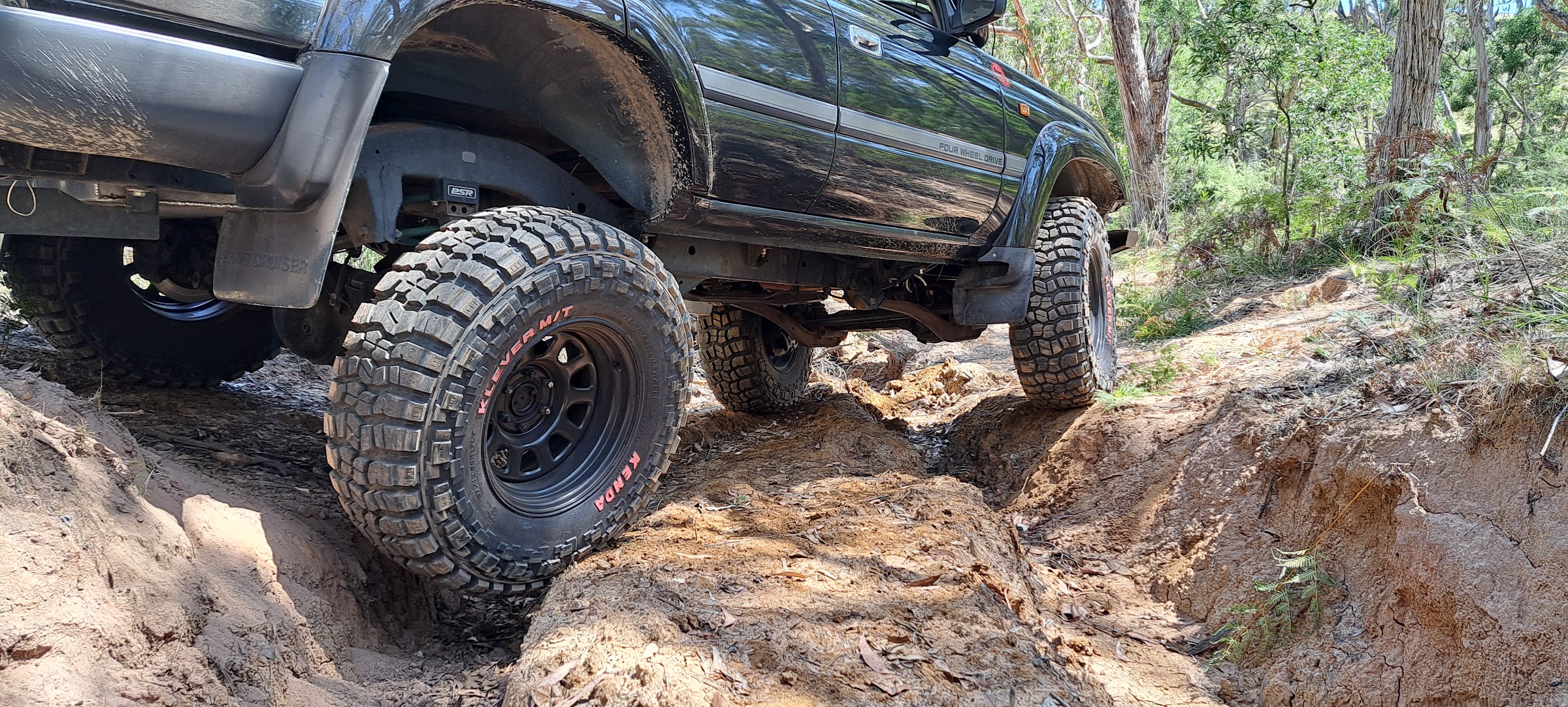 Close view of a four wheel drive on mud terrain tyres crossing deep ruts
